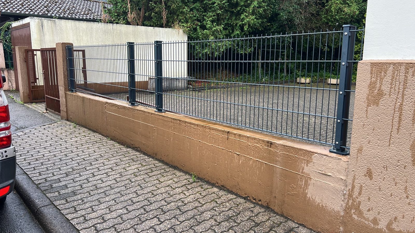 Neue anthrazitfarbene Doppelstabmattenzaun-Anlage mit Tor auf der sanierten Hofmauer