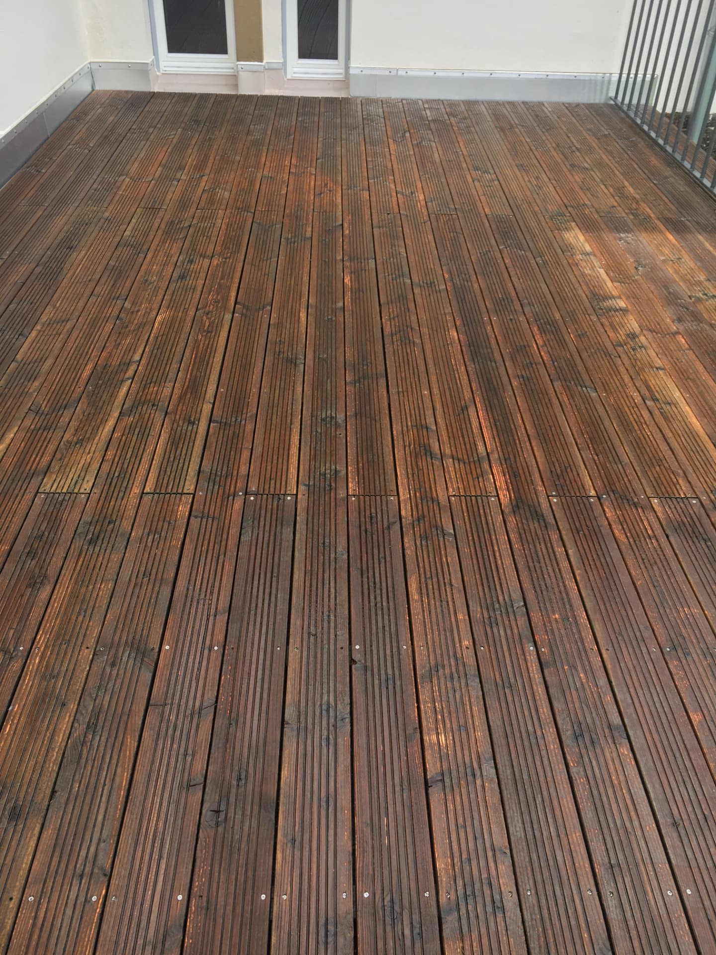 Gereinigte und nachbehandelte Holzterrasse mit gleichmäßig dunkler Oberfläche
