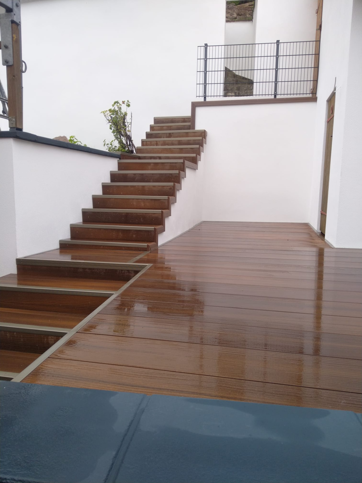WPC-Treppe mit Aluminium-Kantenprofilen entlang einer verputzten Wand