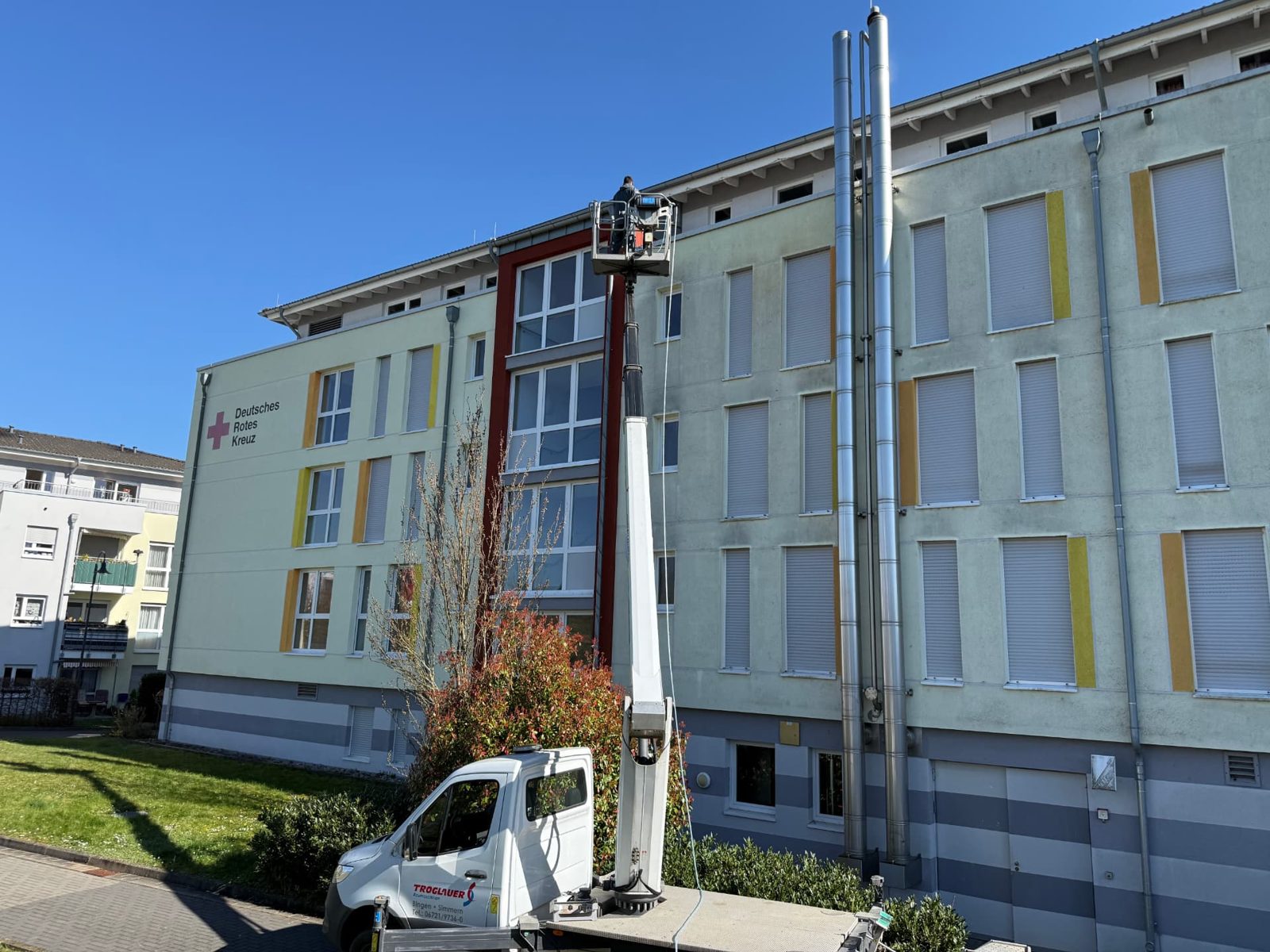 Hebebühne vor der Fassade des DRK-Gebäudes, Reinigung der oberen Geschosse