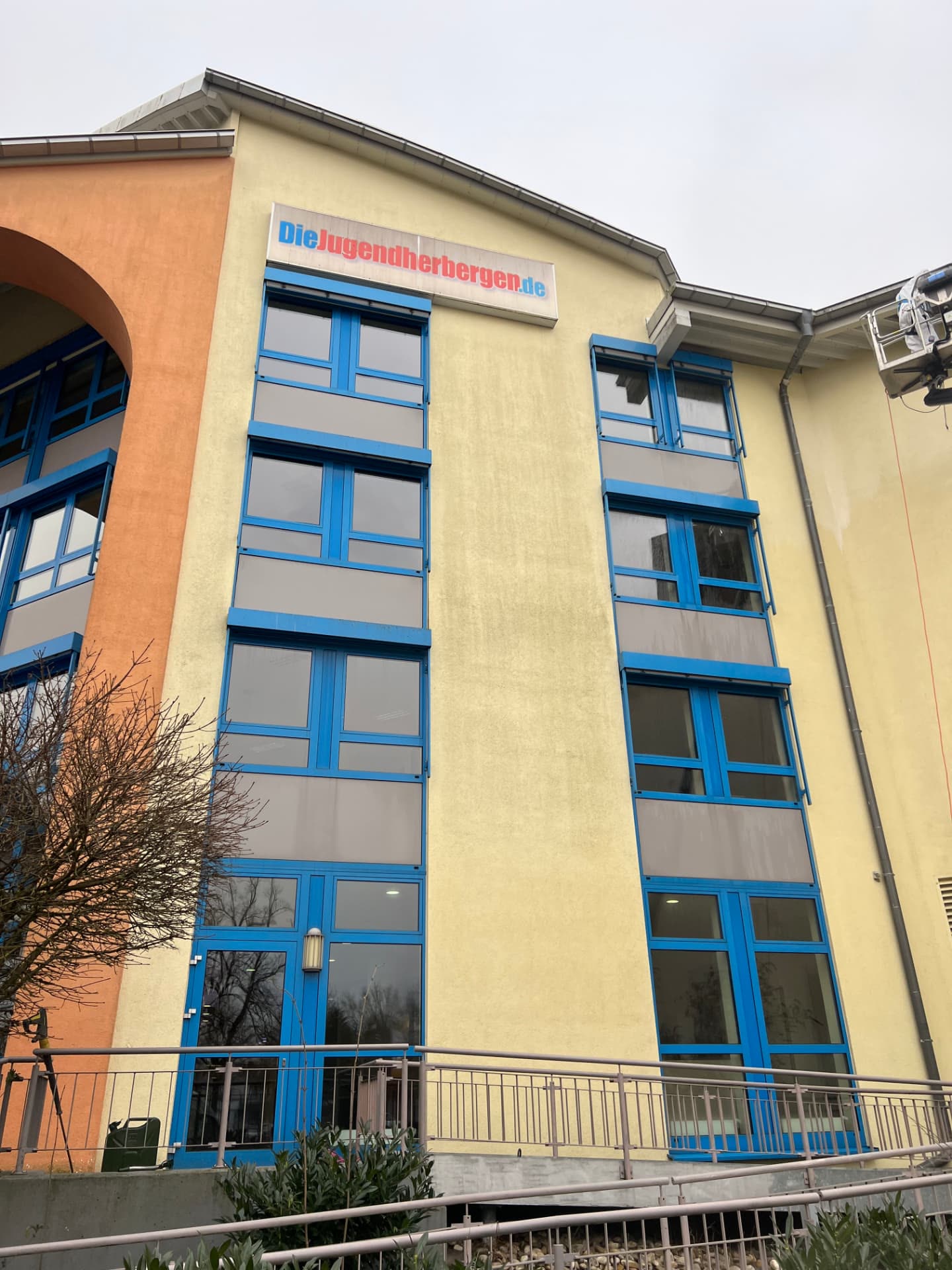 Fassade der Jugendherberge Bad Homburg mit gereinigter Wandfläche, Hebebühne am rechten Gebäudeteil
