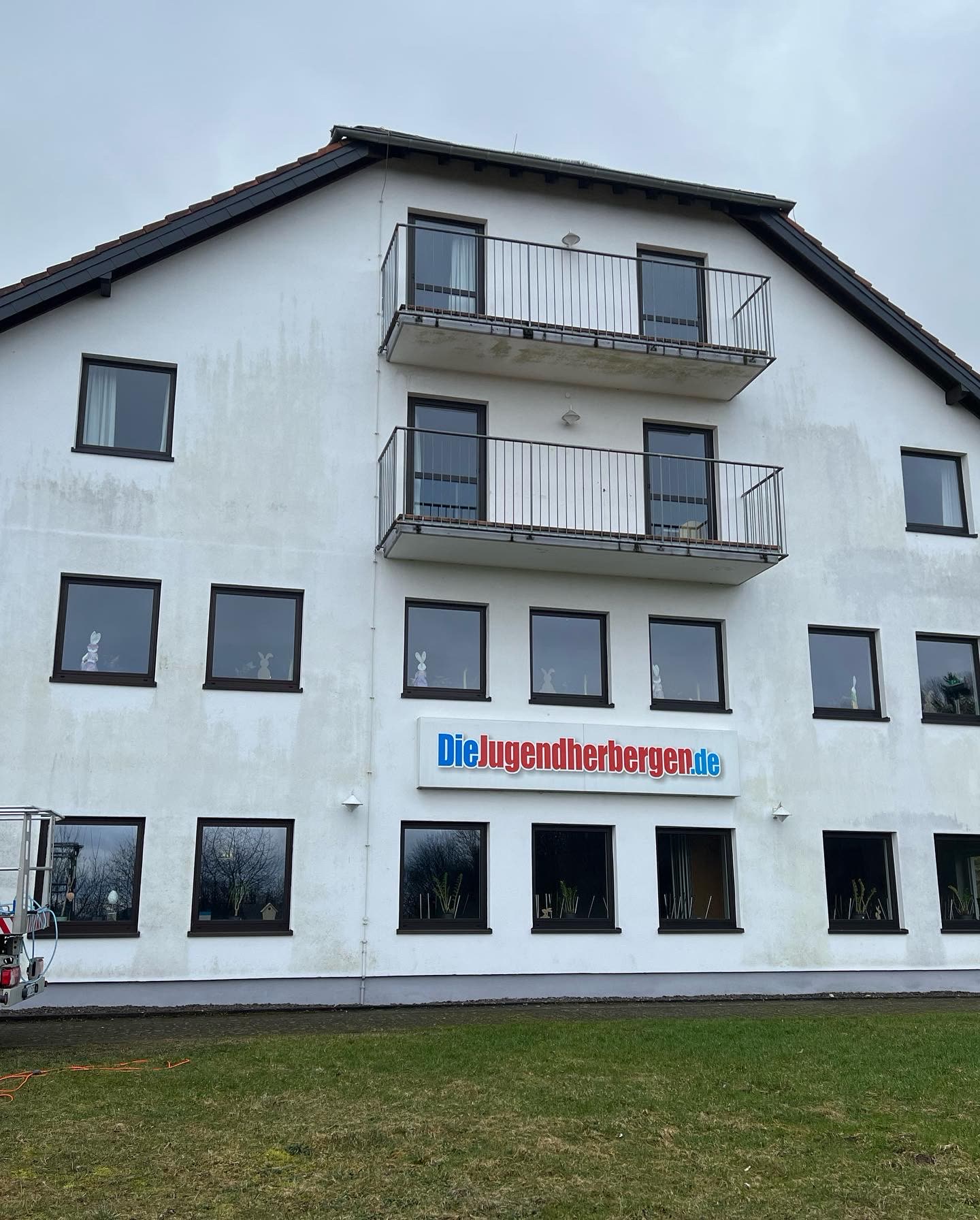Giebelfassade der Jugendherberge Tholey mit Grauschleier und Algenstreifen vor der Reinigung