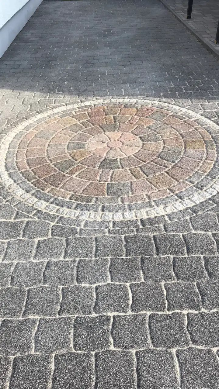 Gereinigtes Betonpflaster mit freigelegtem Ornamentkreis aus Naturstein