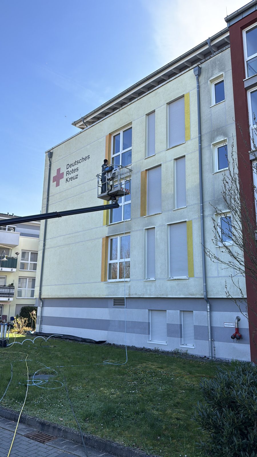 Mitarbeiter reinigt von der Arbeitsbühne aus die Putzfassade des DRK-Objekts in Rüdesheim